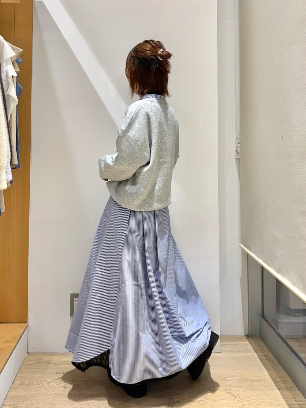 グレー系のニット/セーター、ブルー系のワンピース、ブラック系のスカートを着用したレディースの秋コーディネートの2枚目の写真