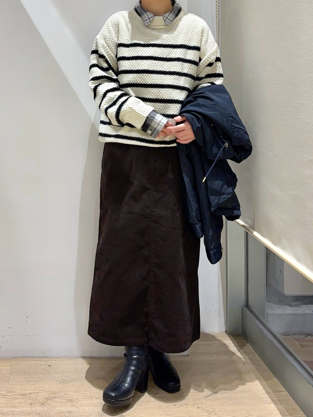 ブラック系のシャツ/ブラウス、ホワイト系のニット/セーター、ブラウン系のスカートを着用したレディースの秋コーディネートの2枚目の写真