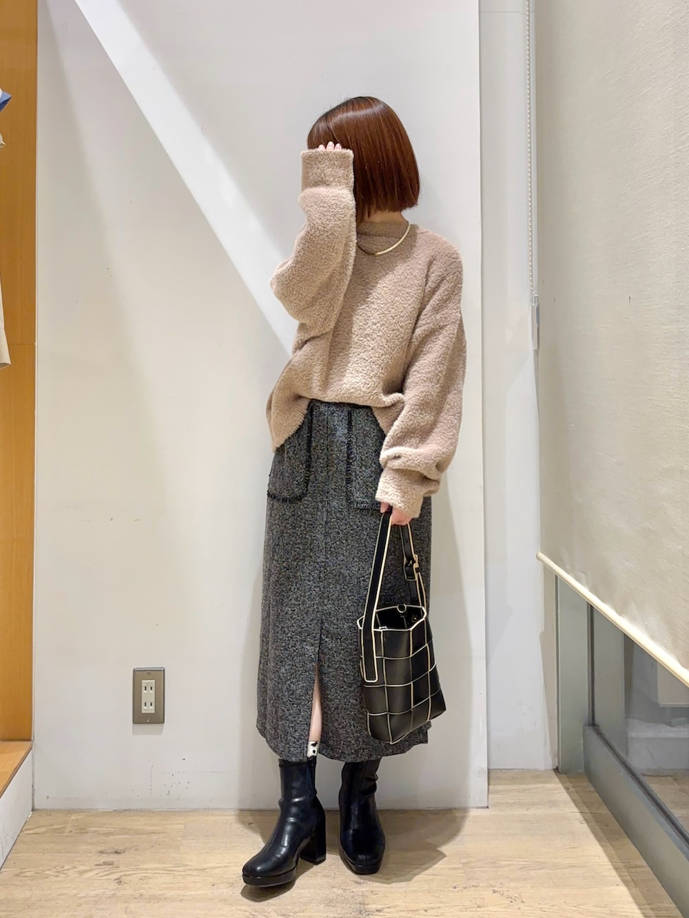 ベージュ系のカーディガン/ボレロ、ホワイト系のスカート、ブラック系のブーツを着用したレディースの秋コーディネートの3枚目の写真