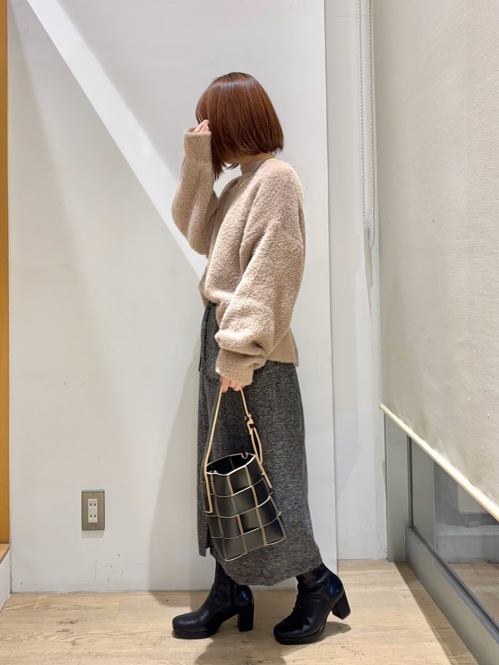 ベージュ系のカーディガン/ボレロ、ホワイト系のスカート、ブラック系のブーツを着用したレディースの秋コーディネートの2枚目の写真