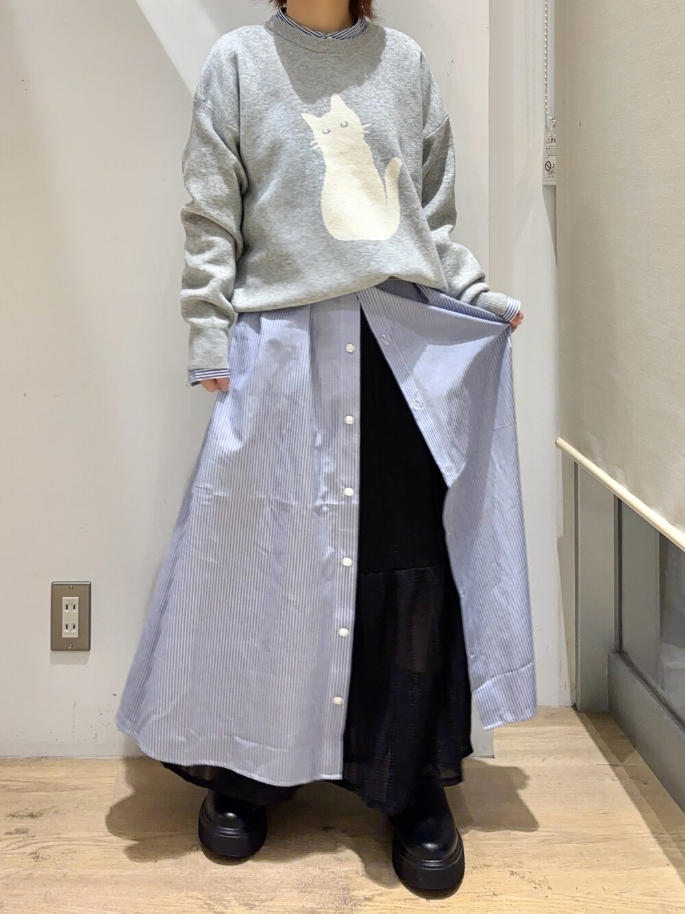 グレー系のニット/セーター、ブルー系のワンピース、ブラック系のスカートを着用したレディースの秋コーディネートの4枚目の写真