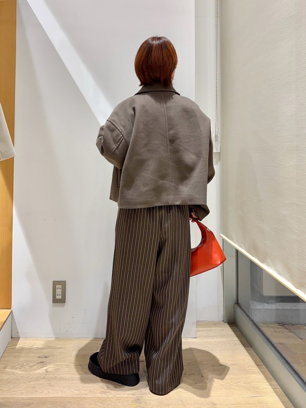 ブラウン系のその他アウター、ブラック系のニット/セーター、レッド系のハンドバッグを着用したレディースの秋コーディネートの2枚目の写真