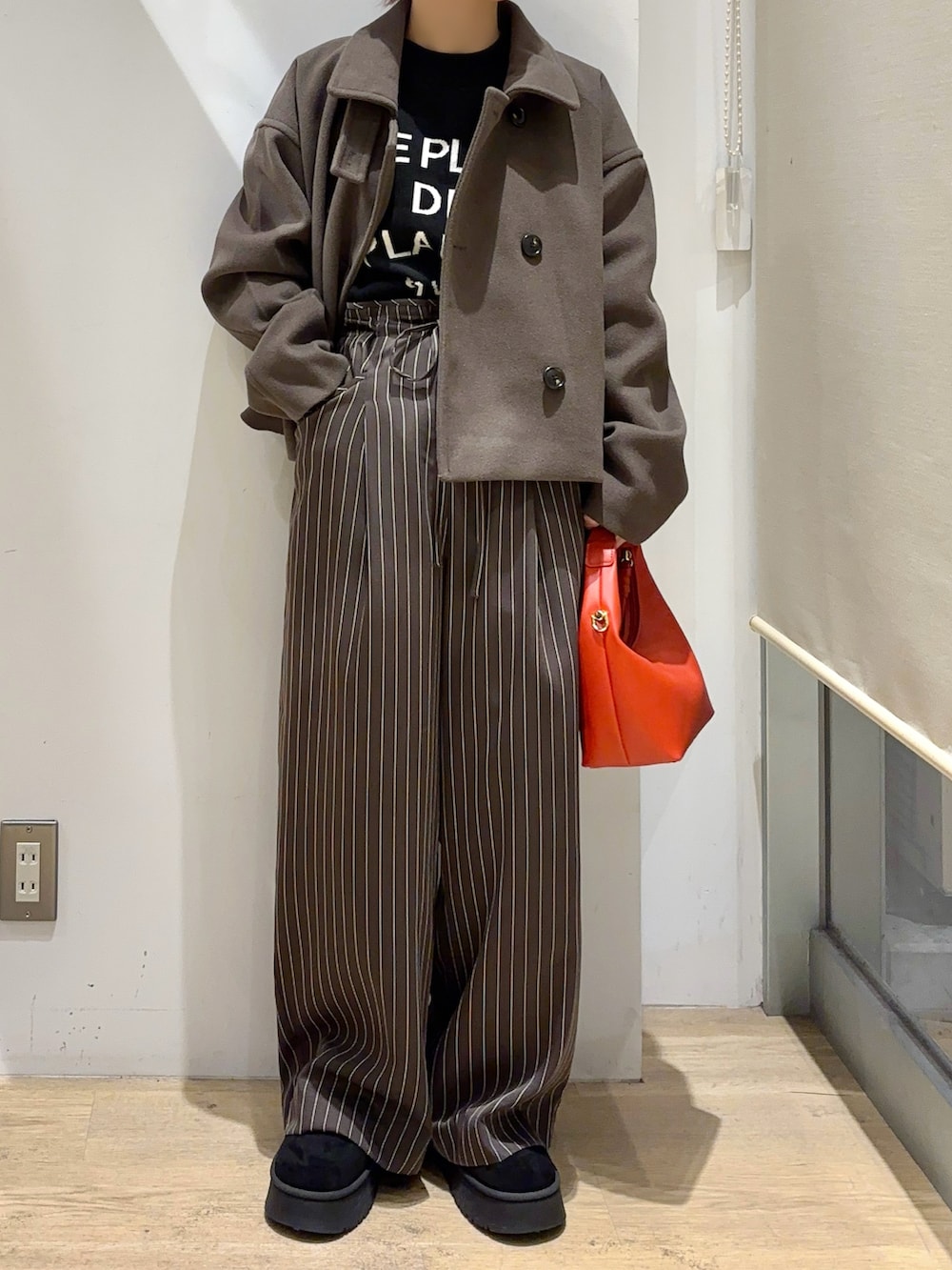 ブラウン系のその他アウター、ブラック系のニット/セーター、レッド系のハンドバッグを着用したレディースの秋コーディネートの3枚目の写真