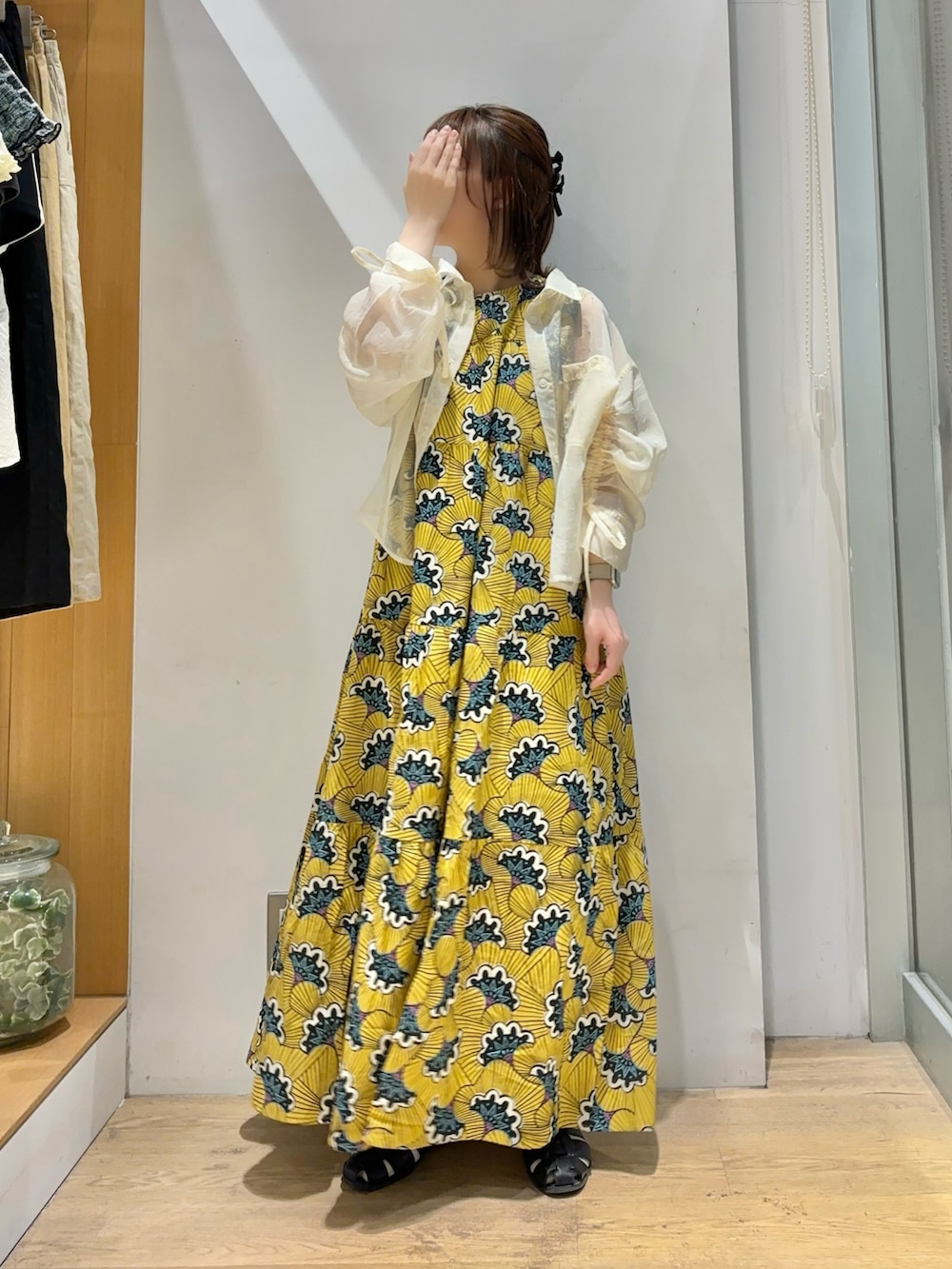 イエロー系のワンピース、ホワイト系のシャツ/ブラウス、ブラック系のサンダルを着用したレディースの夏コーディネートの2枚目の写真