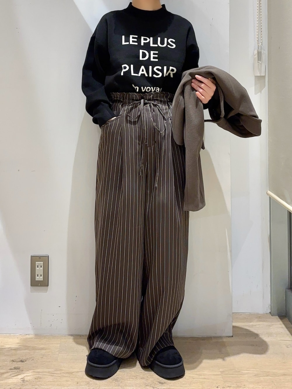 ブラウン系のその他アウター、ブラック系のニット/セーター、レッド系のハンドバッグを着用したレディースの秋コーディネートの4枚目の写真