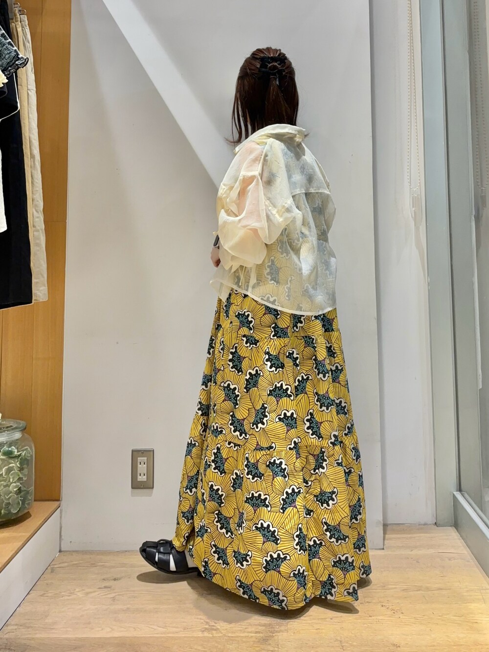 イエロー系のワンピース、ホワイト系のシャツ/ブラウス、ブラック系のサンダルを着用したレディースの夏コーディネートの3枚目の写真
