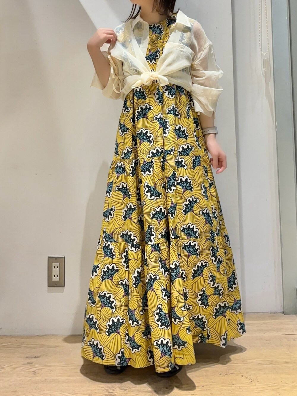 イエロー系のワンピース、ホワイト系のシャツ/ブラウス、ブラック系のサンダルを着用したレディースの夏コーディネートの4枚目の写真