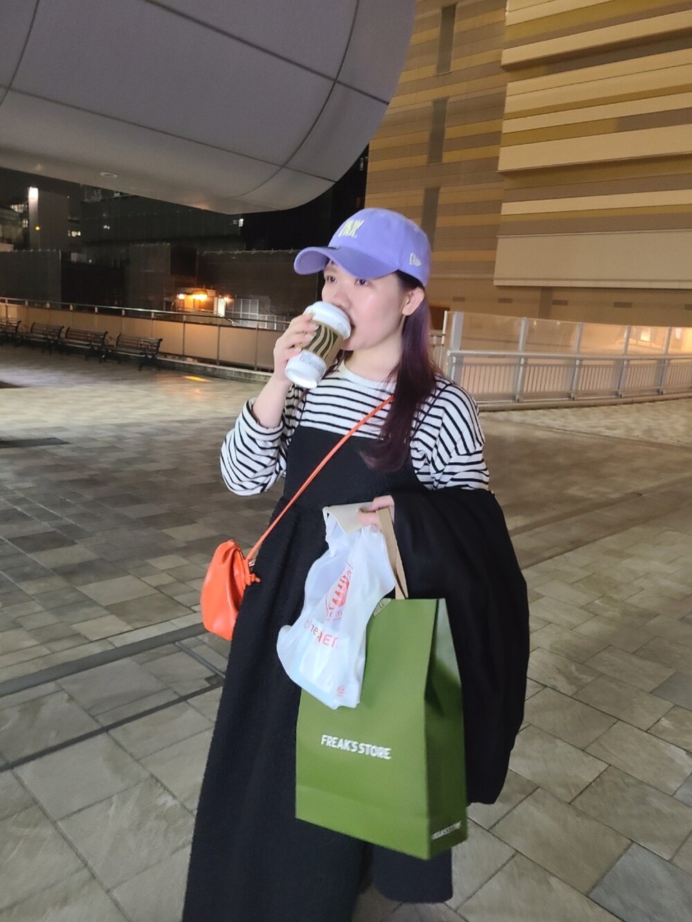 ブラック系のその他アウター、ブラック系のワンピース、オレンジ系のショルダーバッグを着用したレディースの冬コーディネートの2枚目の写真