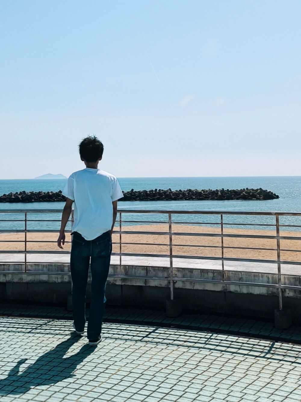ブルー系のデニムパンツ、ホワイト系のTシャツ/カットソー、ブラック系のスニーカーを着用したメンズの春コーディネートの2枚目の写真