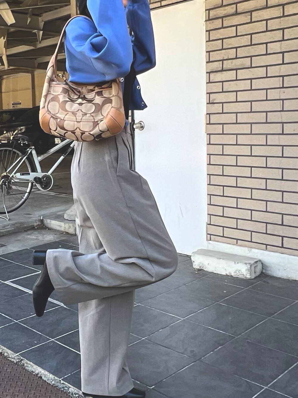 ブラック系のトップス、ブルー系のカーディガン/ボレロ、ブラウン系のパンツを着用したレディースの秋コーディネートの3枚目の写真