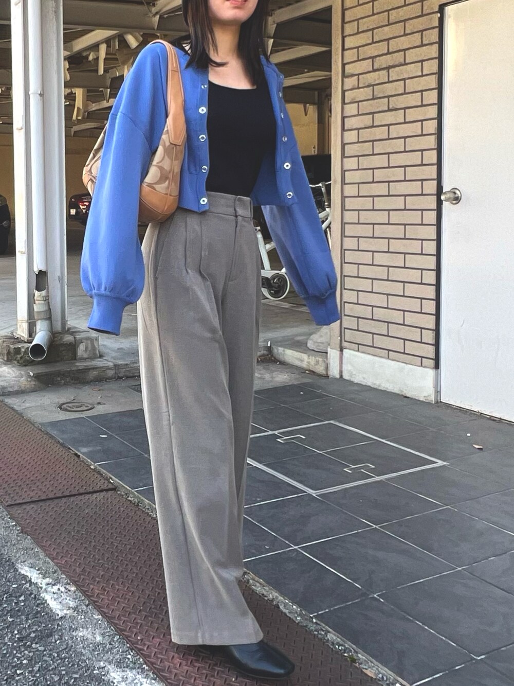 ブラック系のトップス、ブルー系のカーディガン/ボレロ、ブラウン系のパンツを着用したレディースの秋コーディネートの2枚目の写真