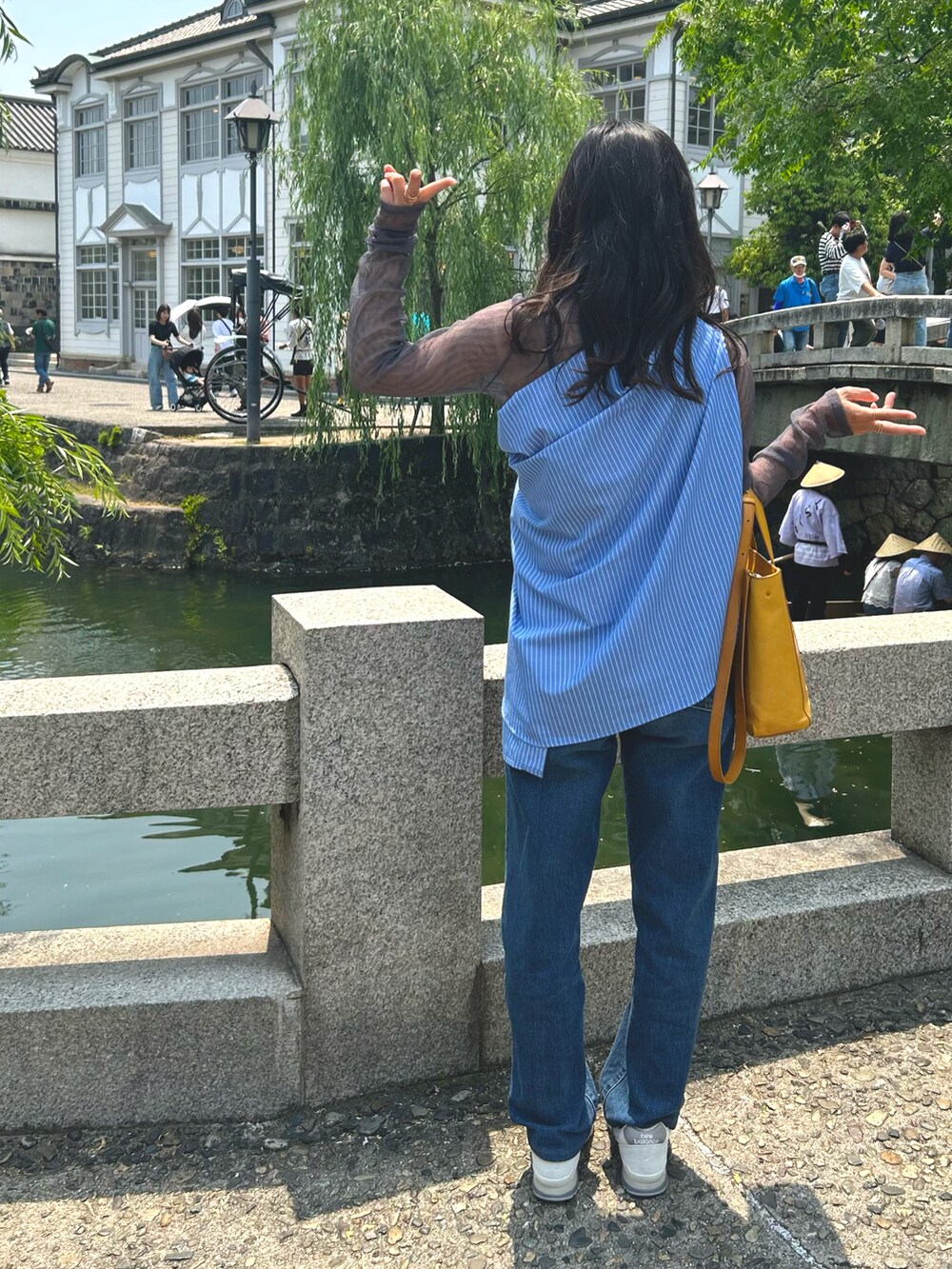イエロー系のトートバッグ、ブルー系のシャツ/ブラウス、グレー系のTシャツ/カットソーを着用したレディースの春コーディネートの2枚目の写真