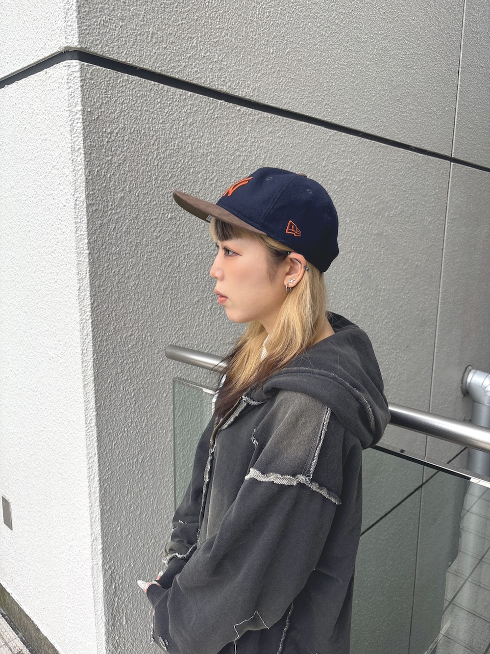 ブラック系のパーカー、ブルー系のデニムパンツ、ブラック系のスニーカーを着用したレディースの秋コーディネートの3枚目の写真