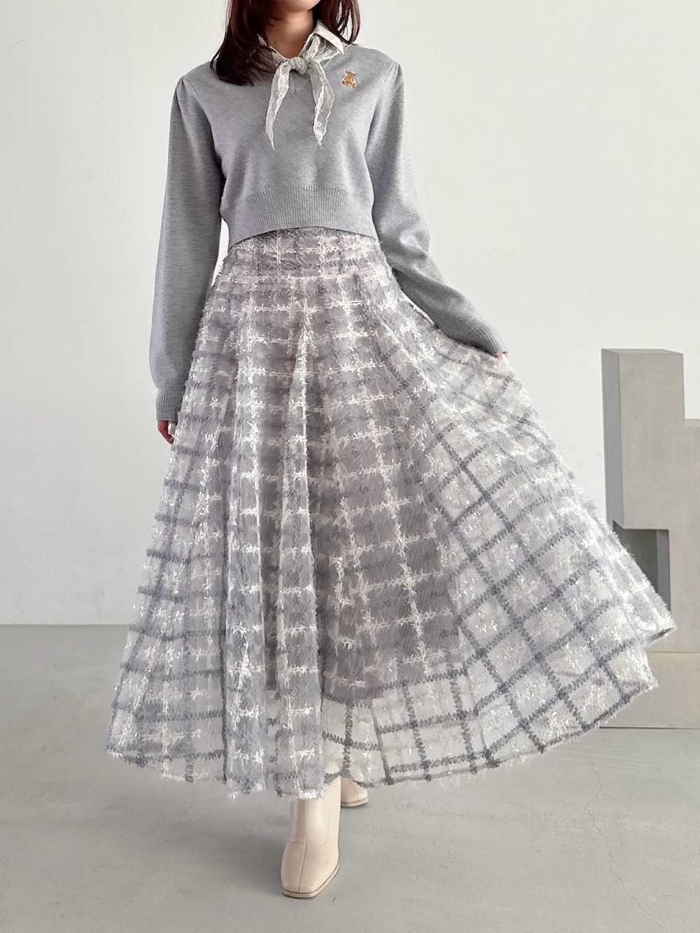 グレー系のニット/セーター、パープル系のスカートを着用したレディースの秋コーディネートの3枚目の写真