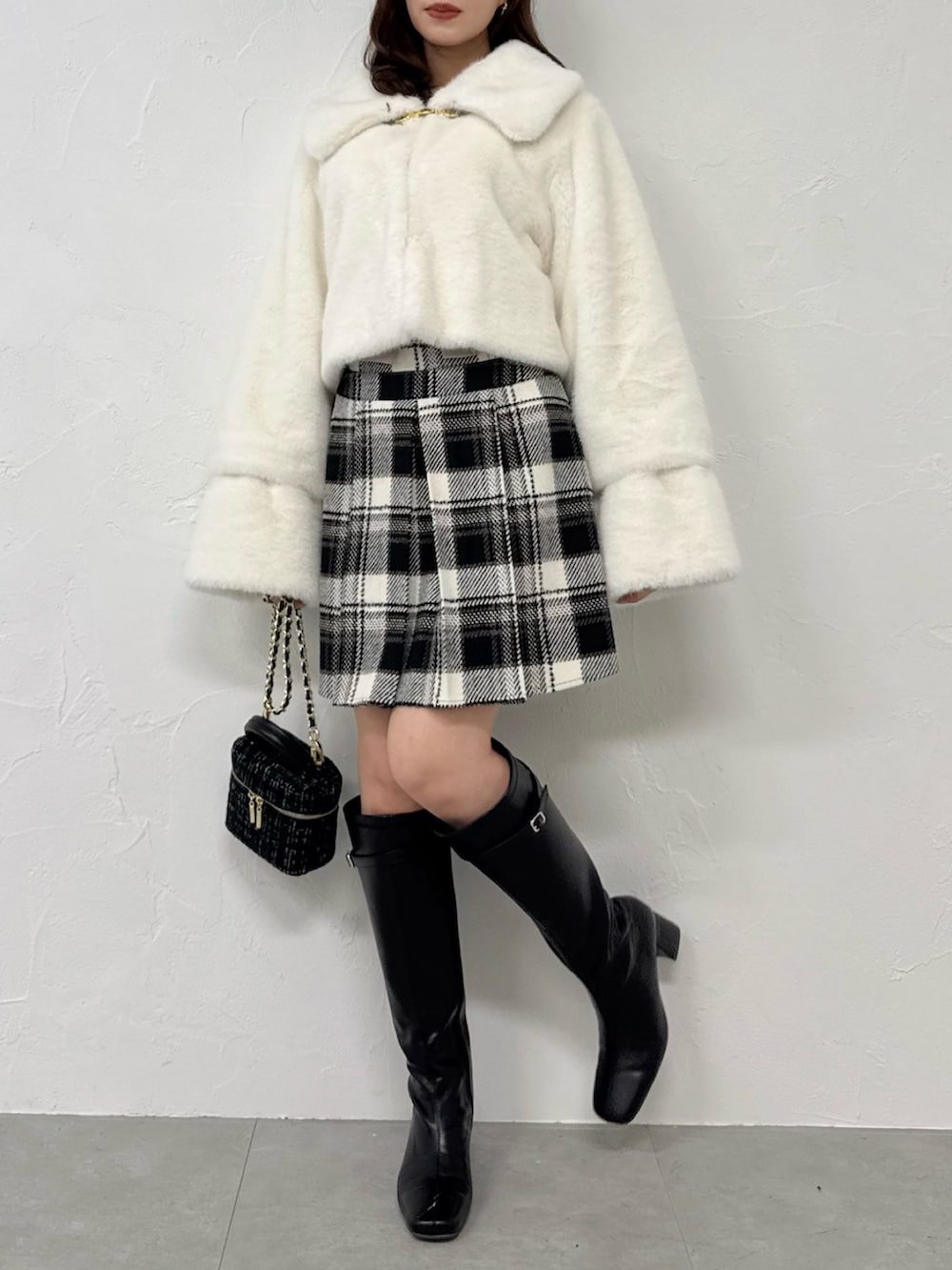 ホワイト系のその他アウター、ブラック系のスカート、ブラック系のブーツを着用したレディースの冬コーディネートの4枚目の写真