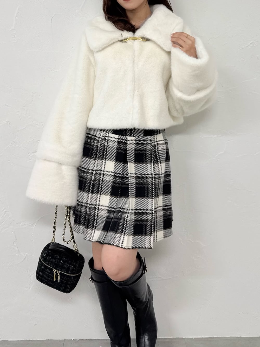 ホワイト系のその他アウター、ブラック系のスカート、ブラック系のブーツを着用したレディースの冬コーディネートの6枚目の写真