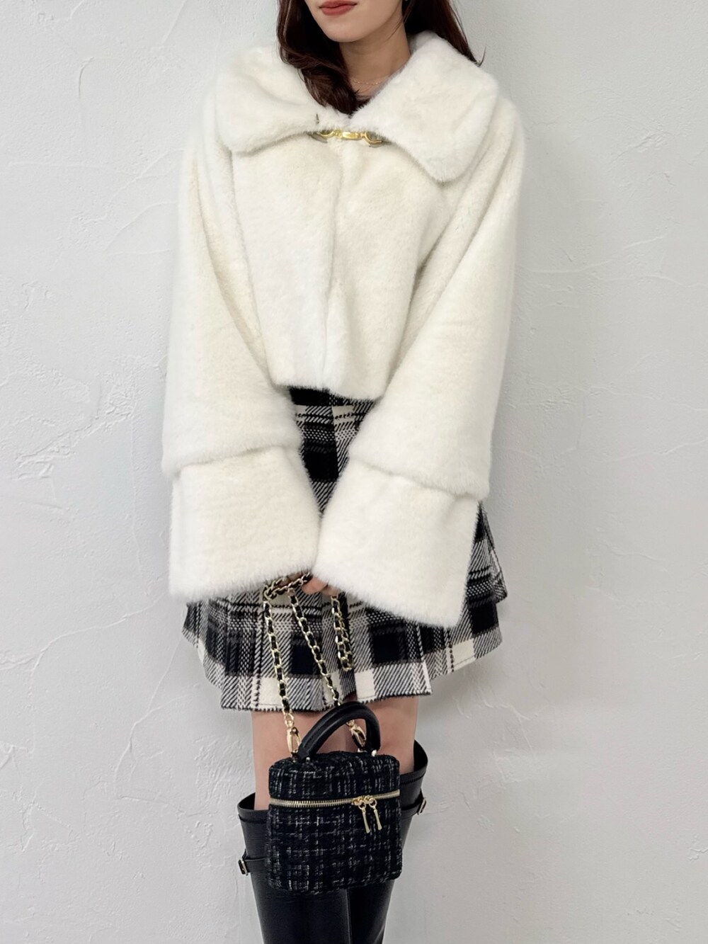 ホワイト系のその他アウター、ブラック系のスカート、ブラック系のブーツを着用したレディースの冬コーディネートの9枚目の写真