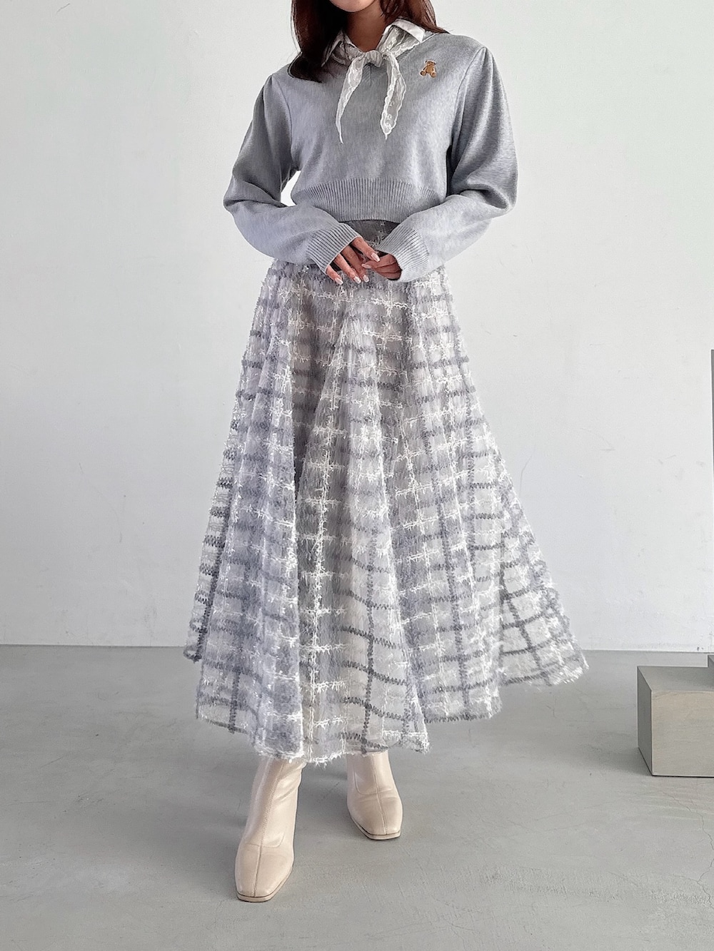 グレー系のニット/セーター、パープル系のスカートを着用したレディースの秋コーディネートの2枚目の写真