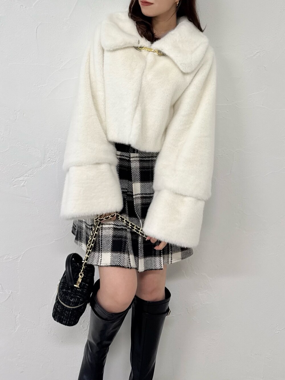 ホワイト系のその他アウター、ブラック系のスカート、ブラック系のブーツを着用したレディースの冬コーディネートの7枚目の写真