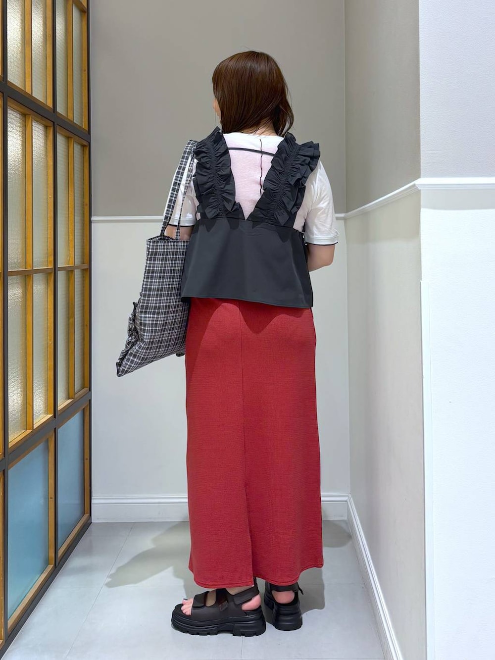 レッド系のスカート、ブラック系のトートバッグ、ブラウン系のサンダルを着用したレディースの夏コーディネートの3枚目の写真