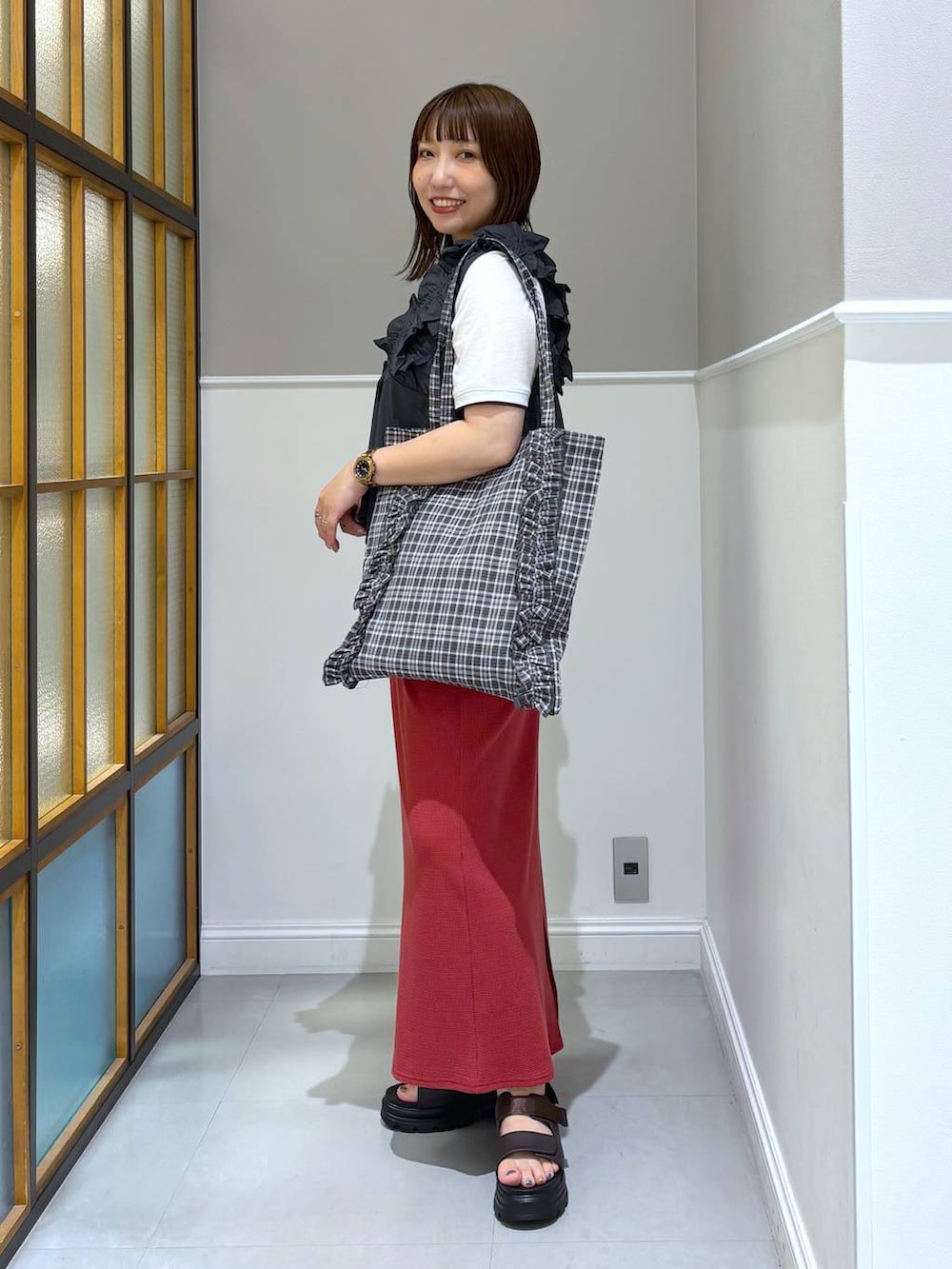 レッド系のスカート、ブラック系のトートバッグ、ブラウン系のサンダルを着用したレディースの夏コーディネートの2枚目の写真