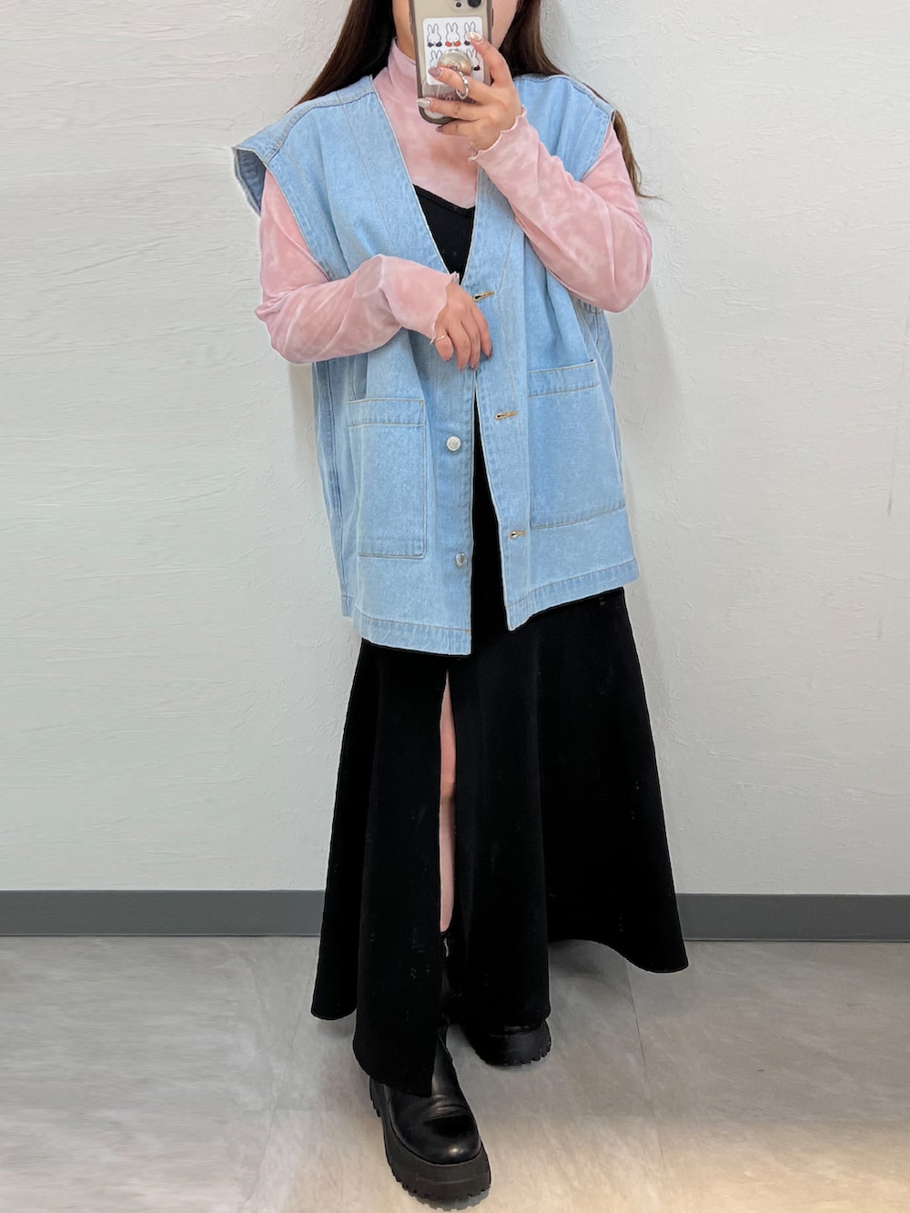 ブルー系のベスト、ブラック系のワンピース、ブラック系のブーツを着用したレディースの春コーディネートの2枚目の写真