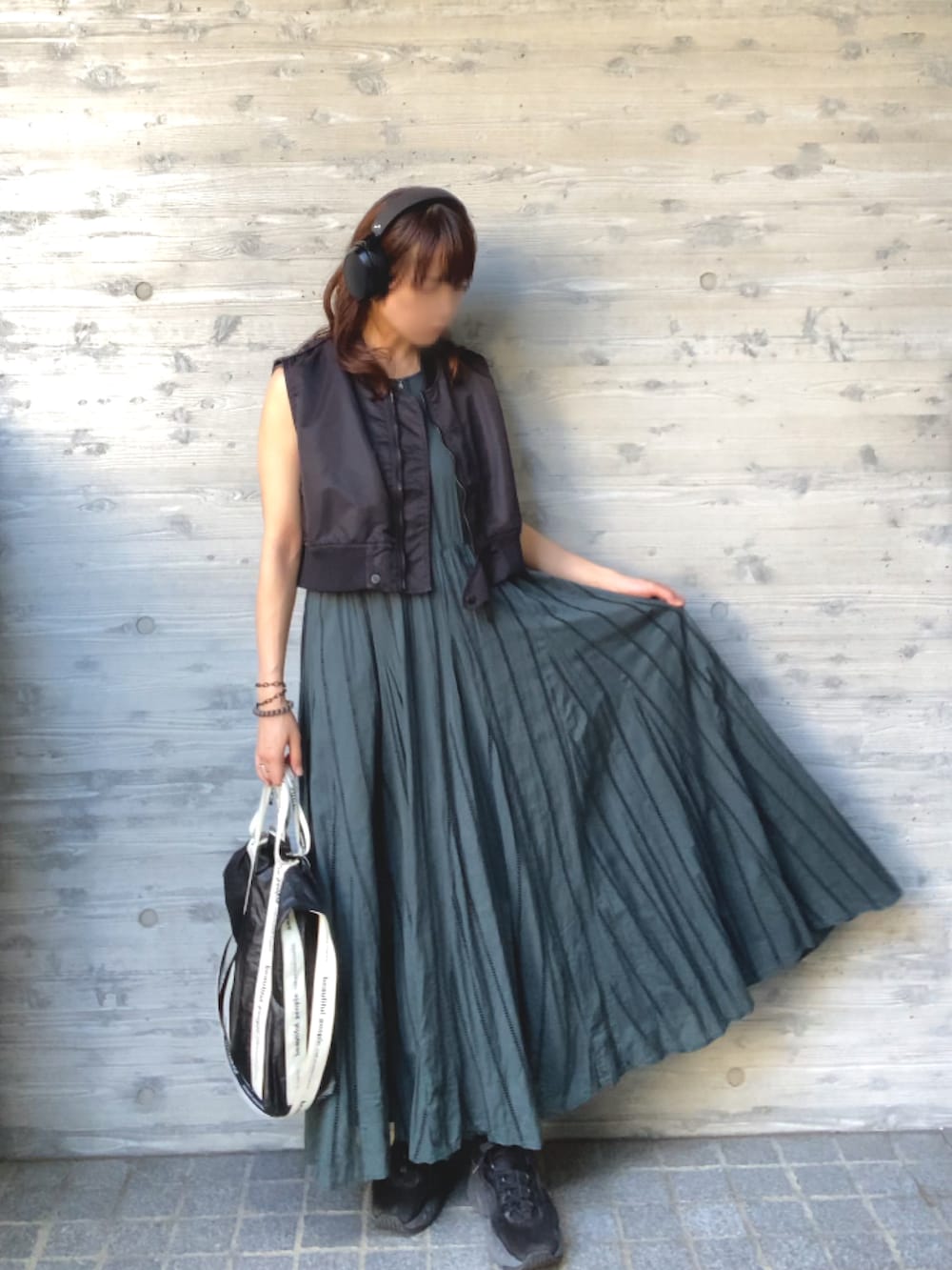 ブラック系のベスト、グリーン系のワンピース/ドレス、ブラック系のスニーカーを着用したレディースの秋コーディネートの3枚目の写真