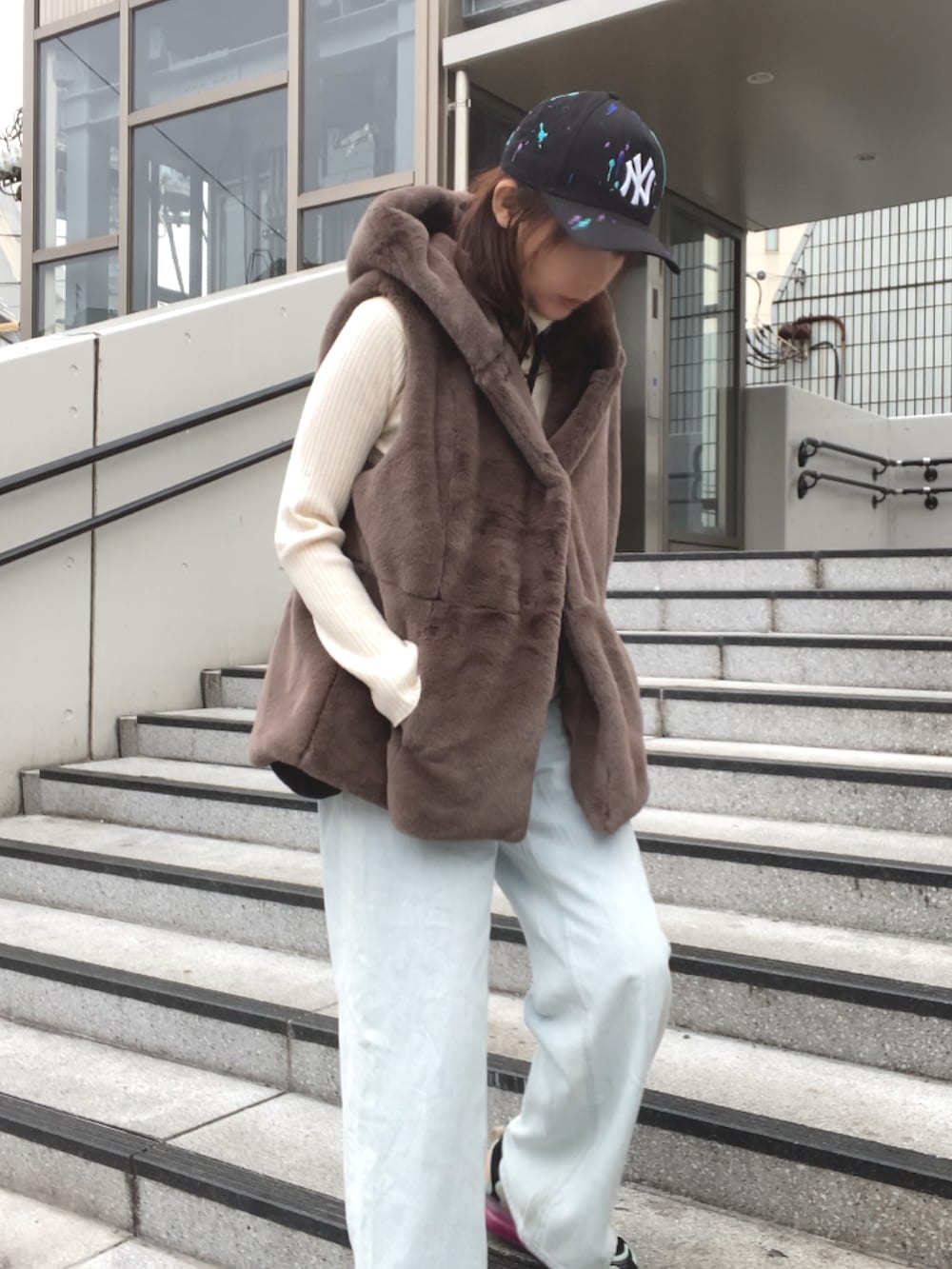 ブラウン系のベスト、ブルー系のデニムパンツ、ブラック系のスニーカーを着用したレディースの冬コーディネートの3枚目の写真