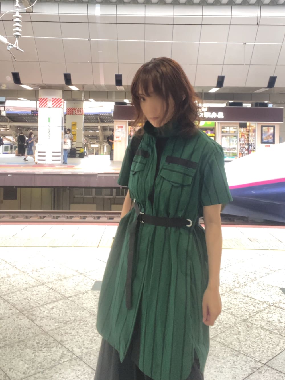 グリーン系のワンピース/ドレス、ブラック系のスカート、ブラック系のスニーカーを着用したレディースの秋コーディネートの3枚目の写真