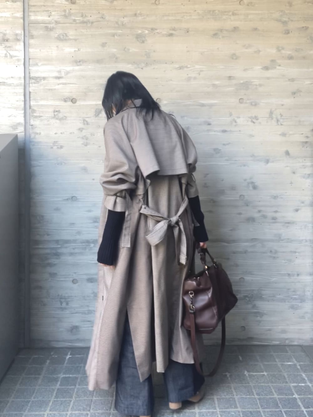 ブラック系のニット/セーター、ブラウン系のトレンチコート、ブルー系のデニムパンツを着用したレディースの春コーディネートの3枚目の写真