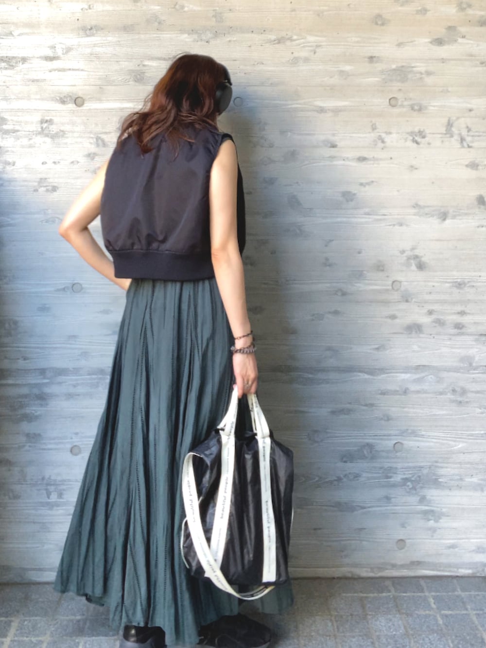 ブラック系のベスト、グリーン系のワンピース/ドレス、ブラック系のスニーカーを着用したレディースの秋コーディネートの2枚目の写真