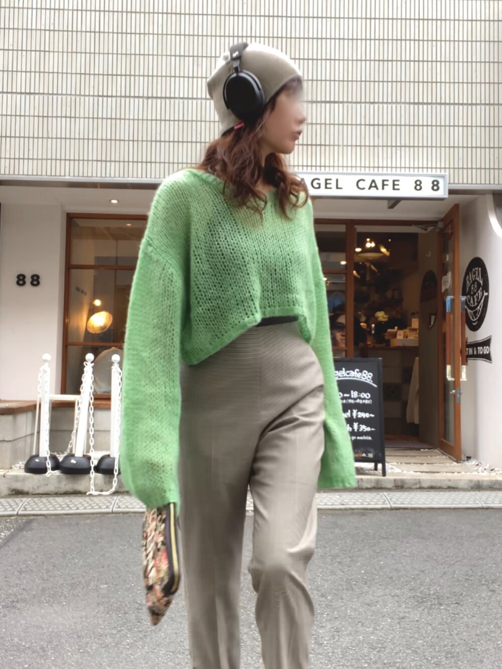 グリーン系のニット/セーター、ブラウン系のパンツ、その他のクラッチバッグを着用したレディースの秋コーディネートの2枚目の写真