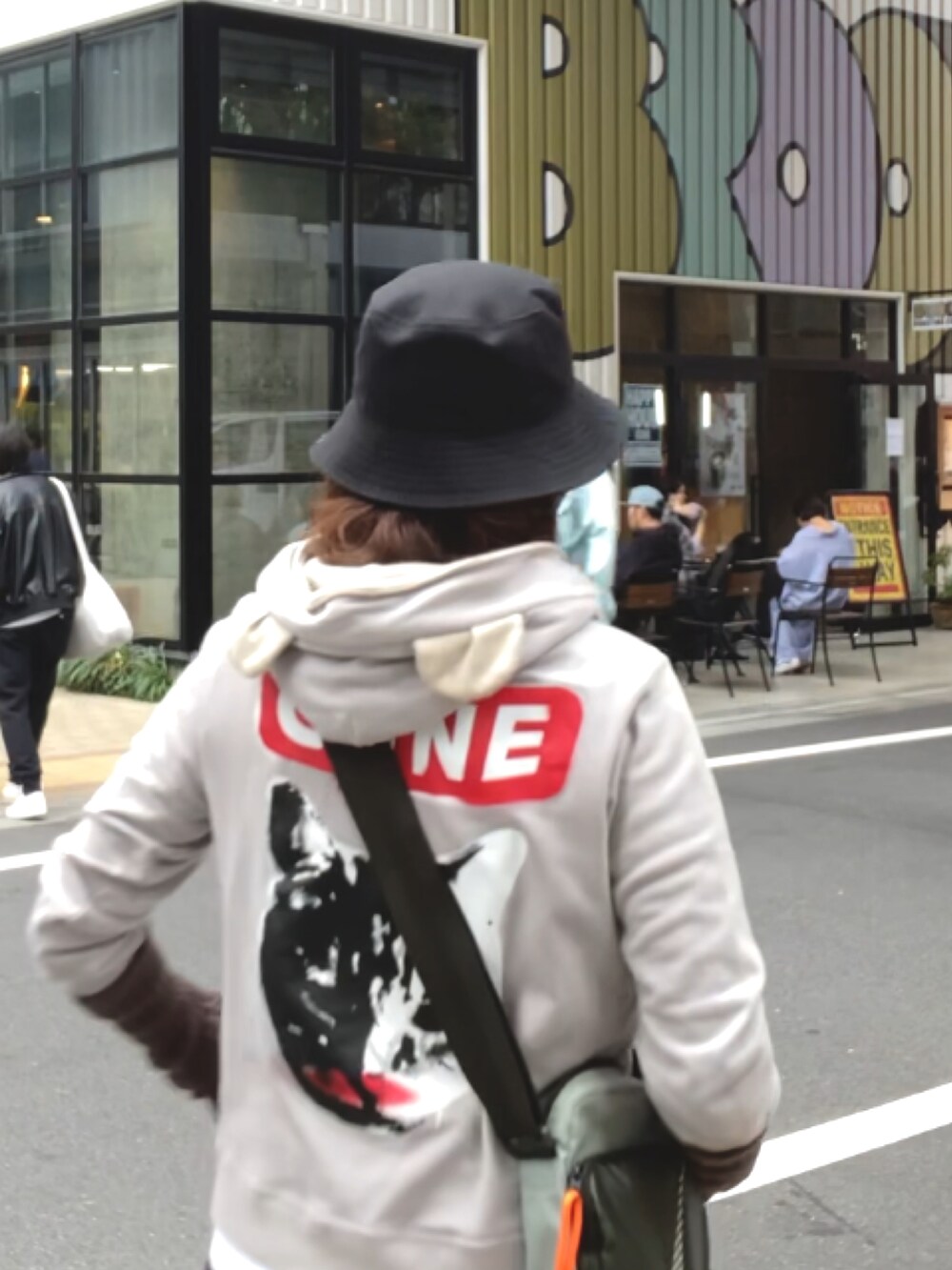 グレー系のパーカー、グレー系のスカート、ブラック系のスニーカーを着用したレディースの秋コーディネートの2枚目の写真