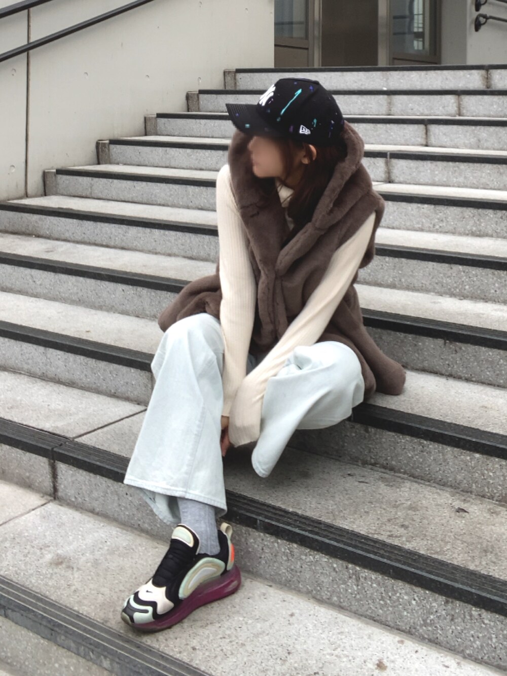 ブラウン系のベスト、ブルー系のデニムパンツ、ブラック系のスニーカーを着用したレディースの冬コーディネートの2枚目の写真