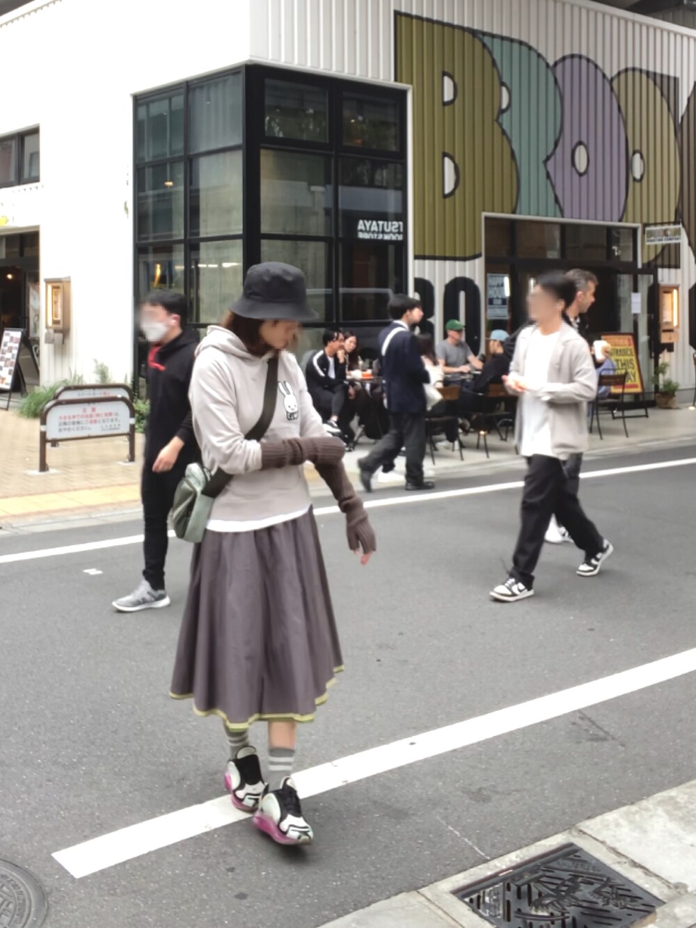 グレー系のパーカー、グレー系のスカート、ブラック系のスニーカーを着用したレディースの秋コーディネートの3枚目の写真