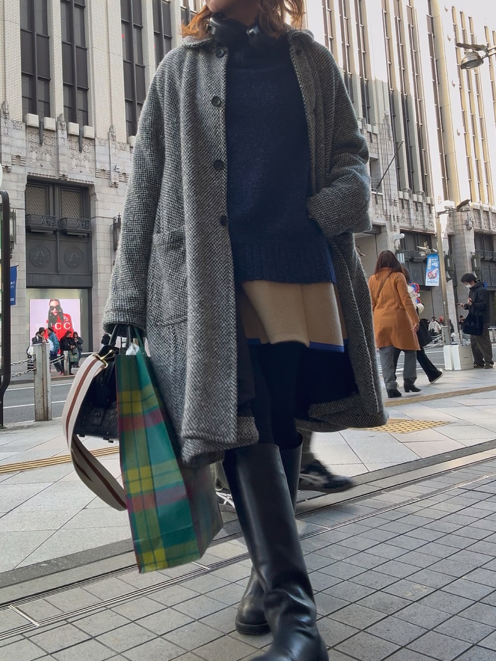 ブルー系のニット/セーター、グレー系のジャケット/アウター、ブラック系のハンドバッグを着用したレディースの冬コーディネートの2枚目の写真