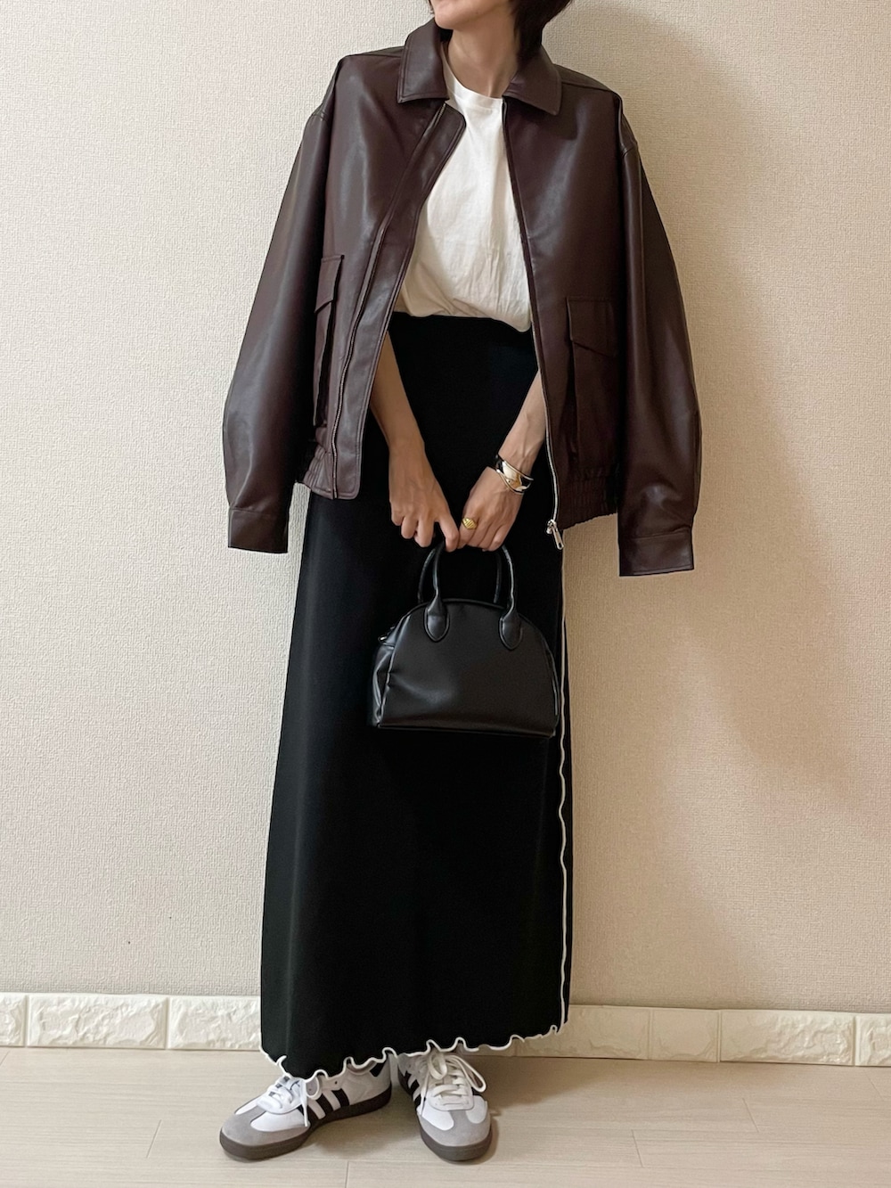 ブラウン系のライダースジャケット、ホワイト系のTシャツ/カットソー、ブラック系のショルダーバッグを着用したレディースの秋コーディネートの2枚目の写真