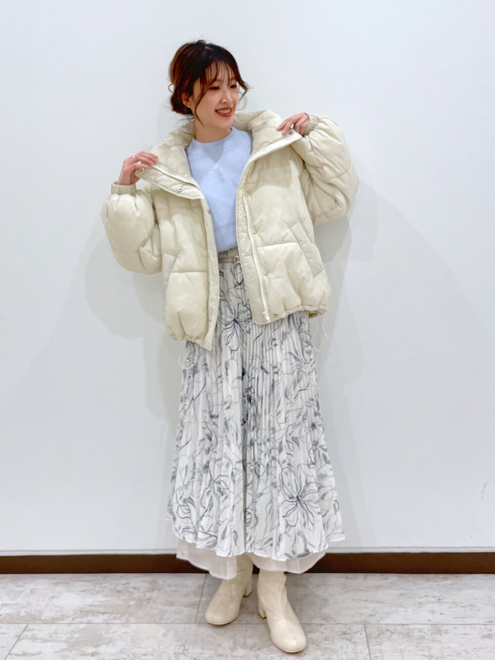 ホワイト系のブルゾン、ブルー系のニット/セーター、ホワイト系のスカートを着用したレディースの冬コーディネートの3枚目の写真