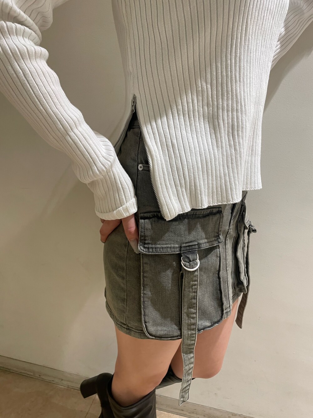 ホワイト系のニット/セーター、ブラック系のデニムスカート、ブラック系のブーツを着用したレディースの秋コーディネートの2枚目の写真