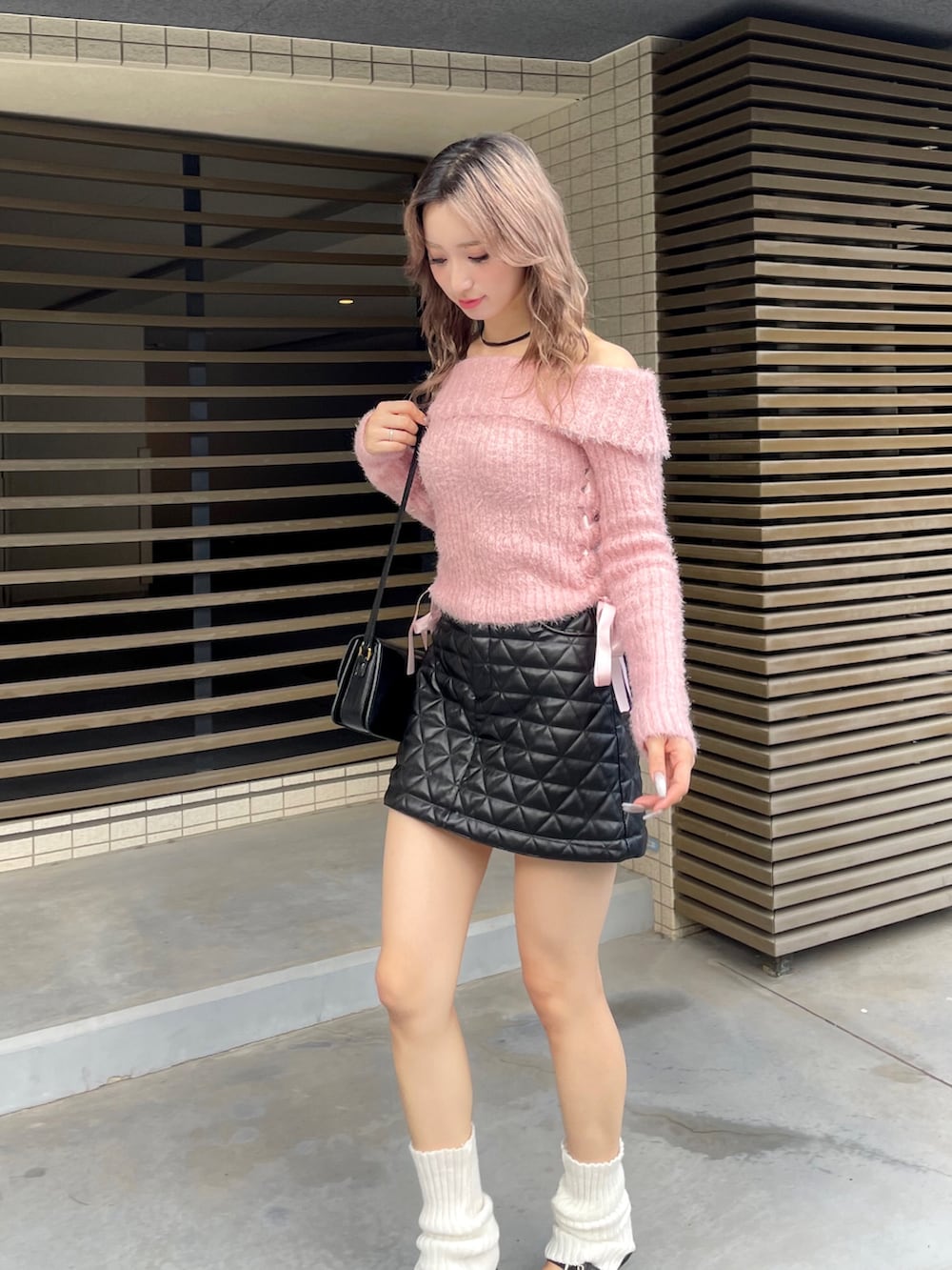 ピンク系のニット/セーター、ブラック系のスカートを着用したレディースの秋コーディネートの2枚目の写真