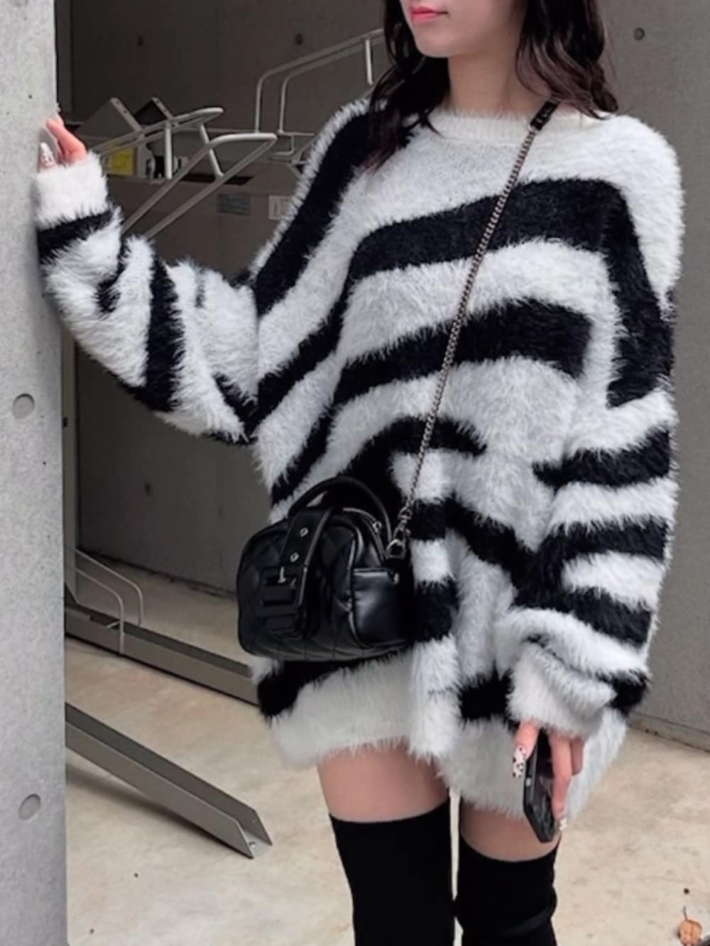 ホワイト系のニット/セーター、ブラック系のショルダーバッグ、ブラック系のブーツを着用したレディースの冬コーディネートの2枚目の写真