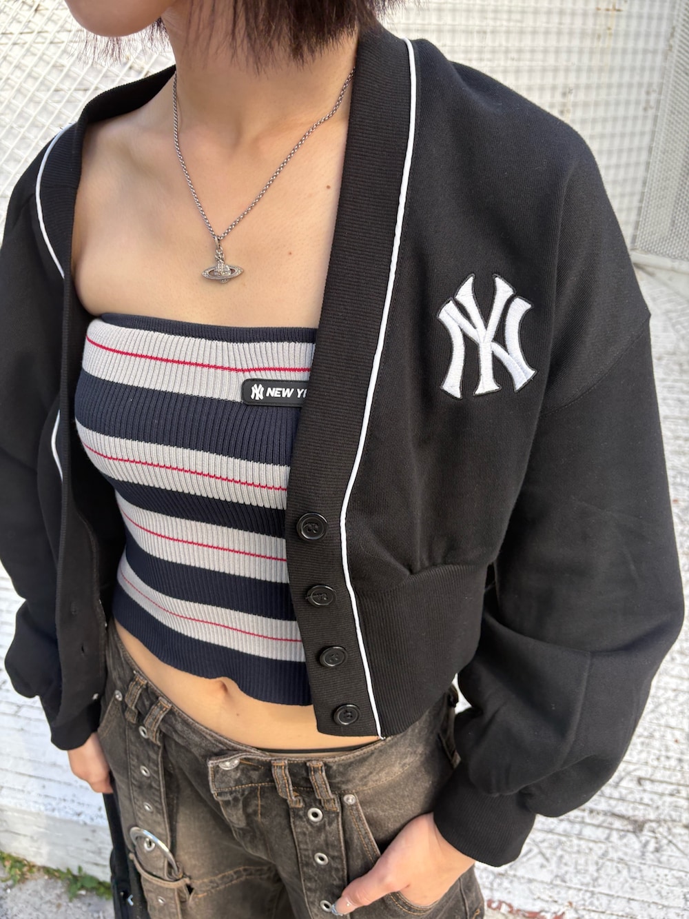 ブラック系のデニムパンツ、ブラック系のハンドバッグ、ブルー系のチューブトップを着用したレディースの夏コーディネートの2枚目の写真