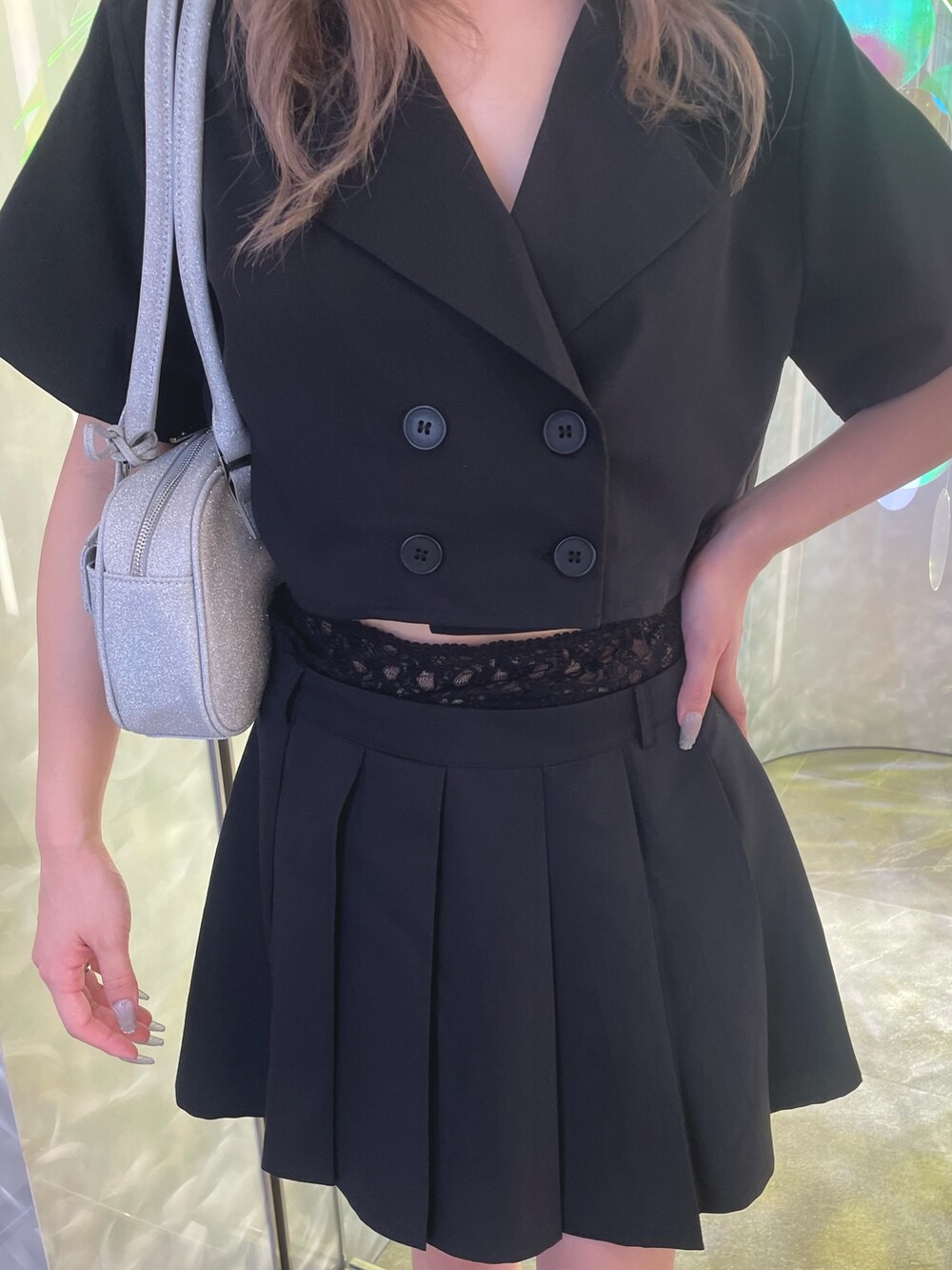 ブラック系のセットアップ、シルバー系のハンドバッグ、ブラック系のサンダルを着用したレディースの夏コーディネートの2枚目の写真