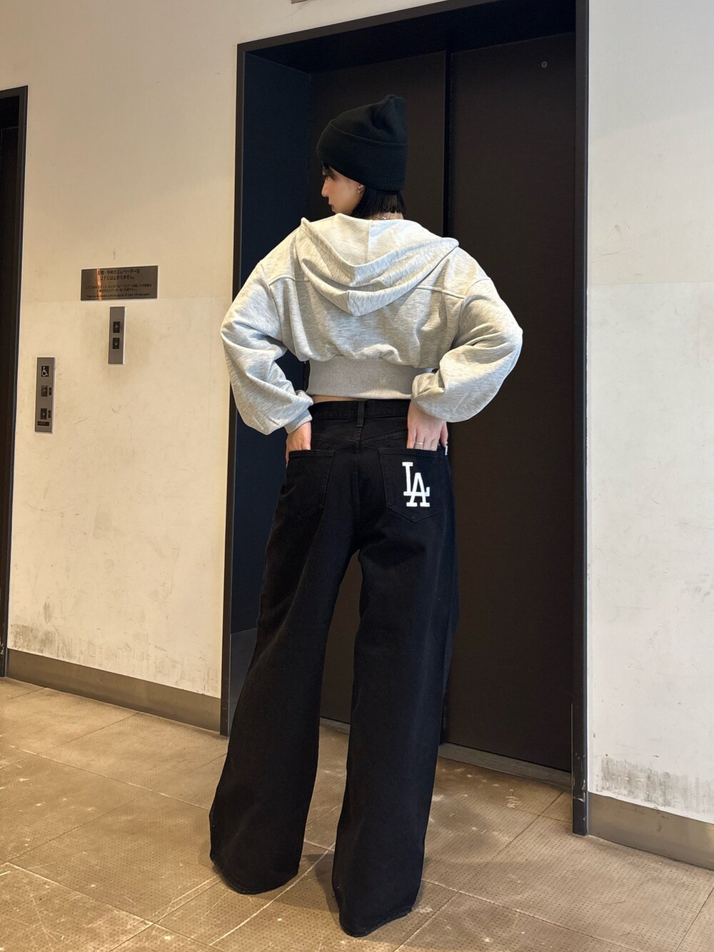 ブラック系のデニムパンツ、ブラック系のキャミソール、グレー系のパーカーを着用したレディースの冬コーディネートの3枚目の写真