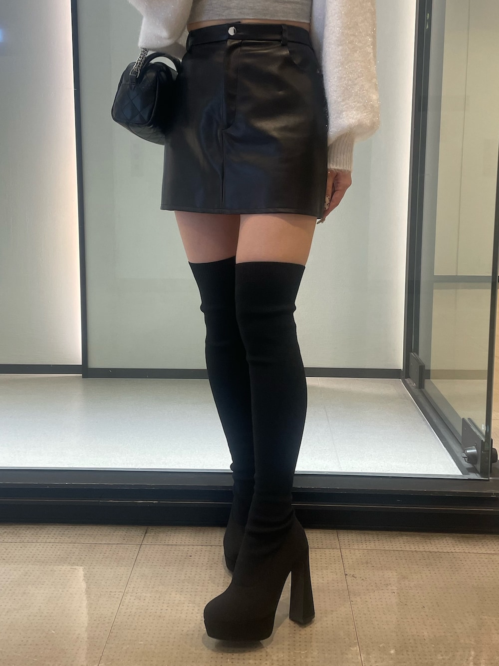 ホワイト系のカーディガン/ボレロ、グレー系のキャミソール、ブラック系のブーツを着用したレディースの秋コーディネートの3枚目の写真