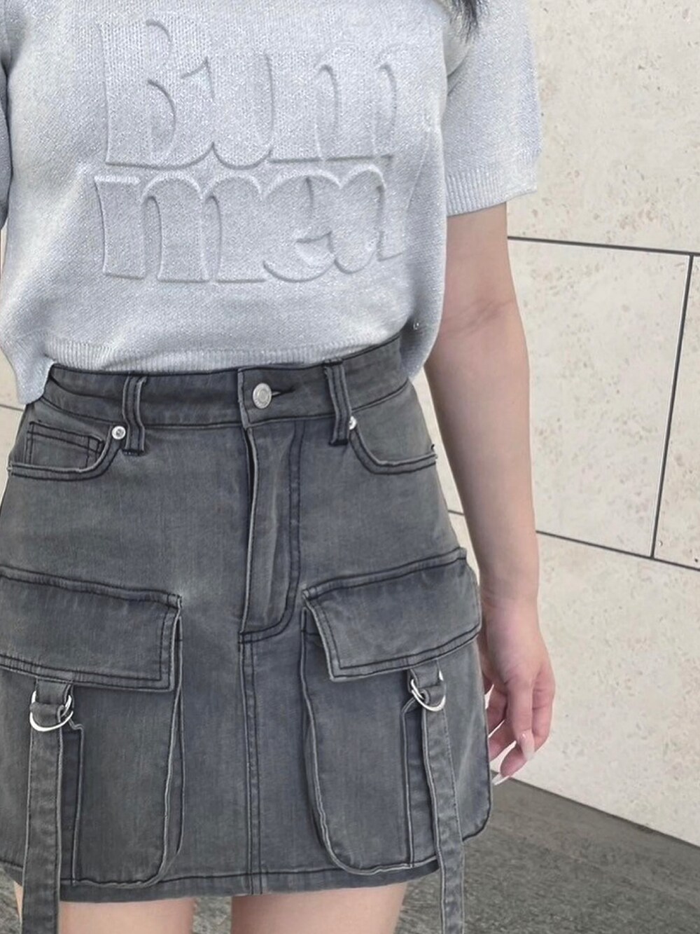 ブラック系のデニムスカート、ホワイト系のニット/セーター、ブラック系のサンダルを着用したレディースの夏コーディネートの3枚目の写真