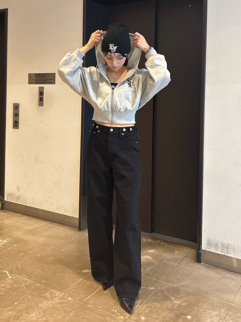 ブラック系のデニムパンツ、ブラック系のキャミソール、グレー系のパーカーを着用したレディースの冬コーディネートの2枚目の写真