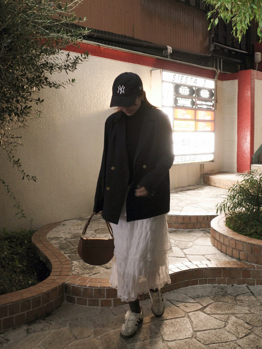 ホワイト系のスカート、ホワイト系のスニーカー、ブラック系のニット/セーターを着用したレディースの冬コーディネートの2枚目の写真