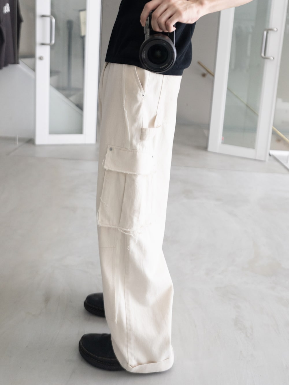 ホワイト系のカーゴパンツ、ブラック系のニット/セーター、ゴールド系のネックレスを着用したメンズの春コーディネートの2枚目の写真