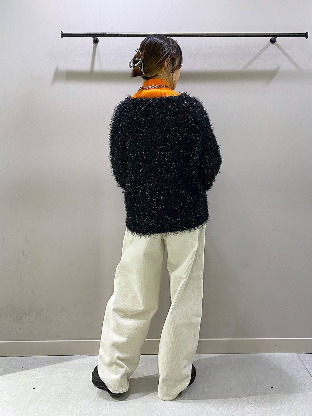 オレンジ系のニット/セーター、ブラック系のブーツ、ホワイト系のその他パンツを着用したレディースの秋コーディネートの3枚目の写真